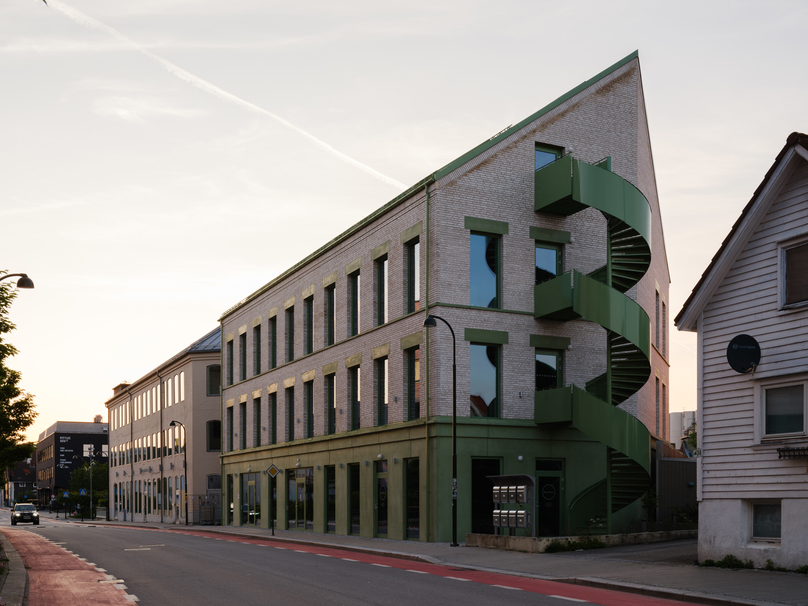 Foto av et mursteinsbygg med grønne detaljer sett fra gate.