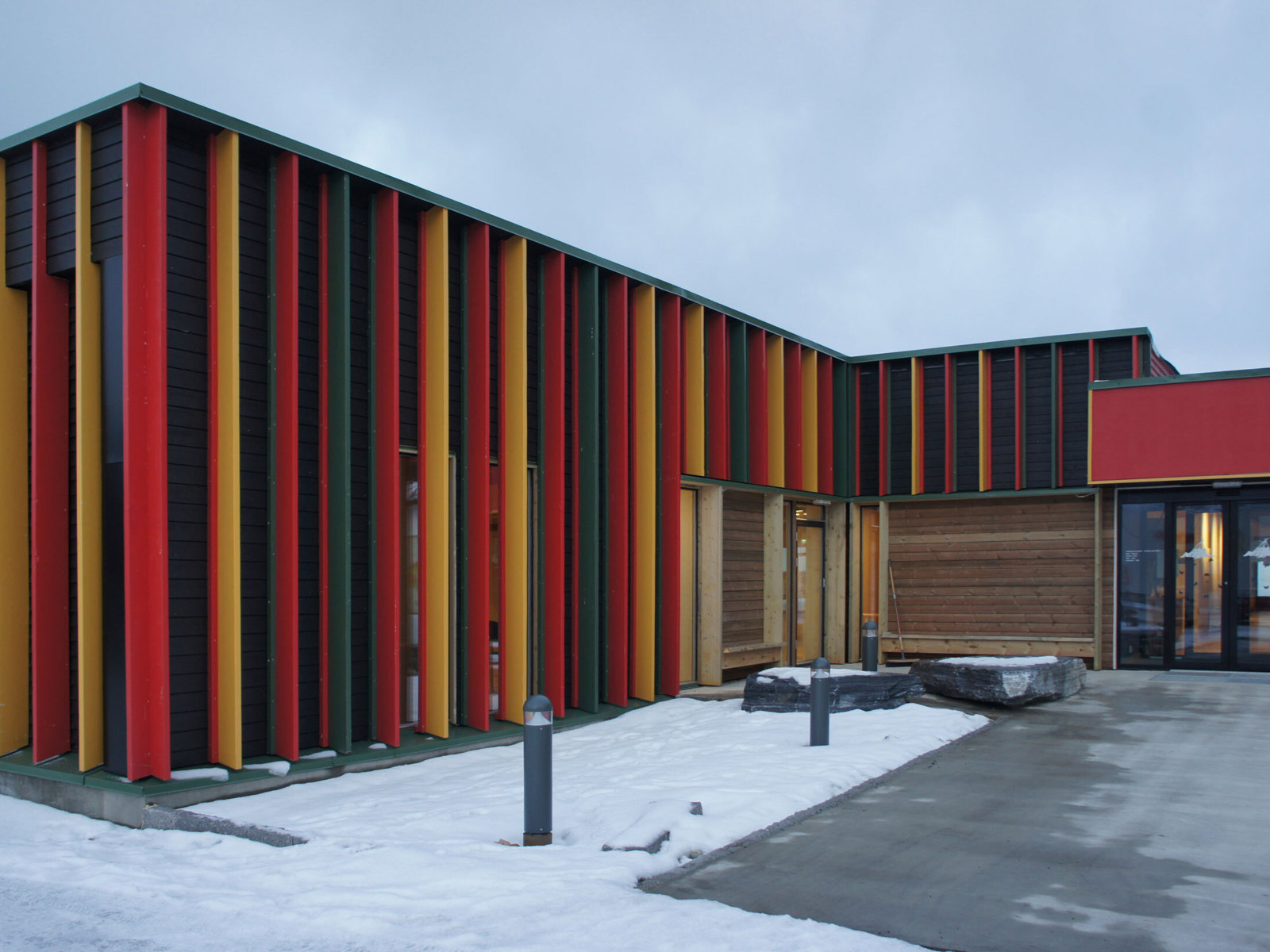 Fargerik fasade med spiler i ulike farger, inngangsdør. Foto.