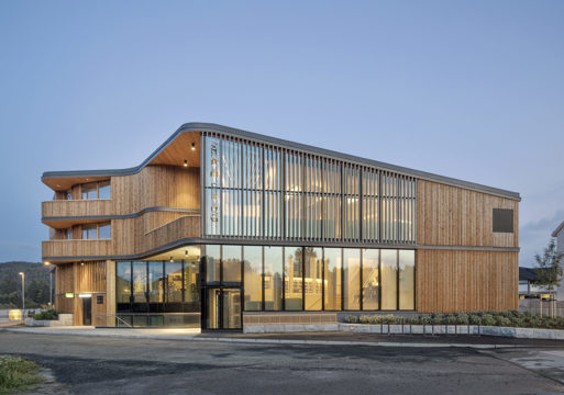 Et bygg med trepanel og glass i fasaden 