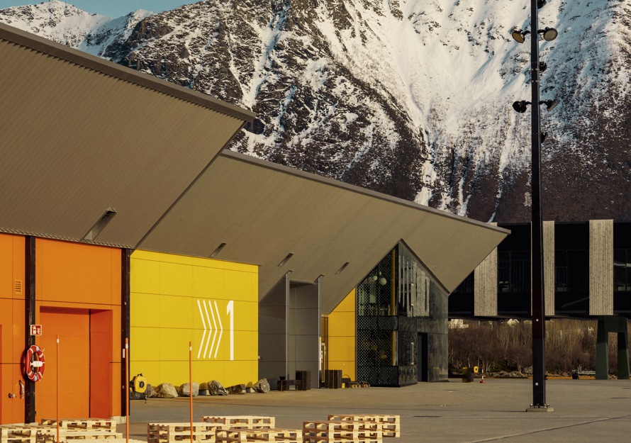 Eksteriørfoto av anlegget som viser et gult og et orange bygg, mens et snødekket fjell stekker seg opp i bakgrunnen