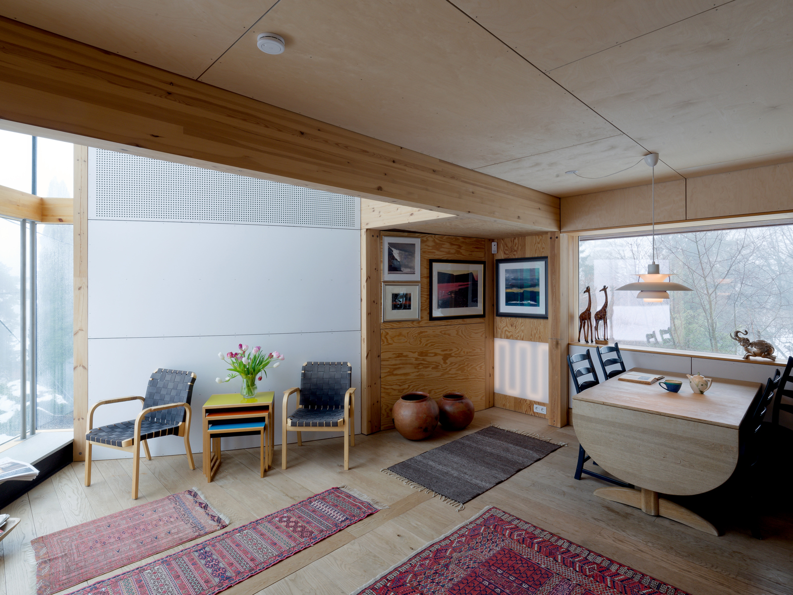 Interiør foto av stue i enebolig, ulike tepper på gulvet og lys inn fra flere kanter.