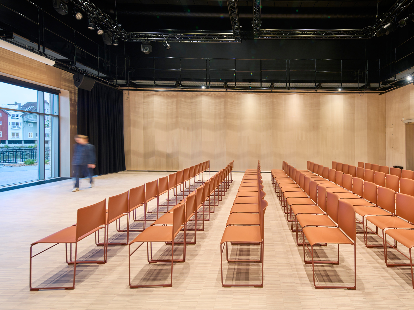 Interiør foto fra en sal på Steinkjær kulturhus, oransje stoler er plassert ut i rader.