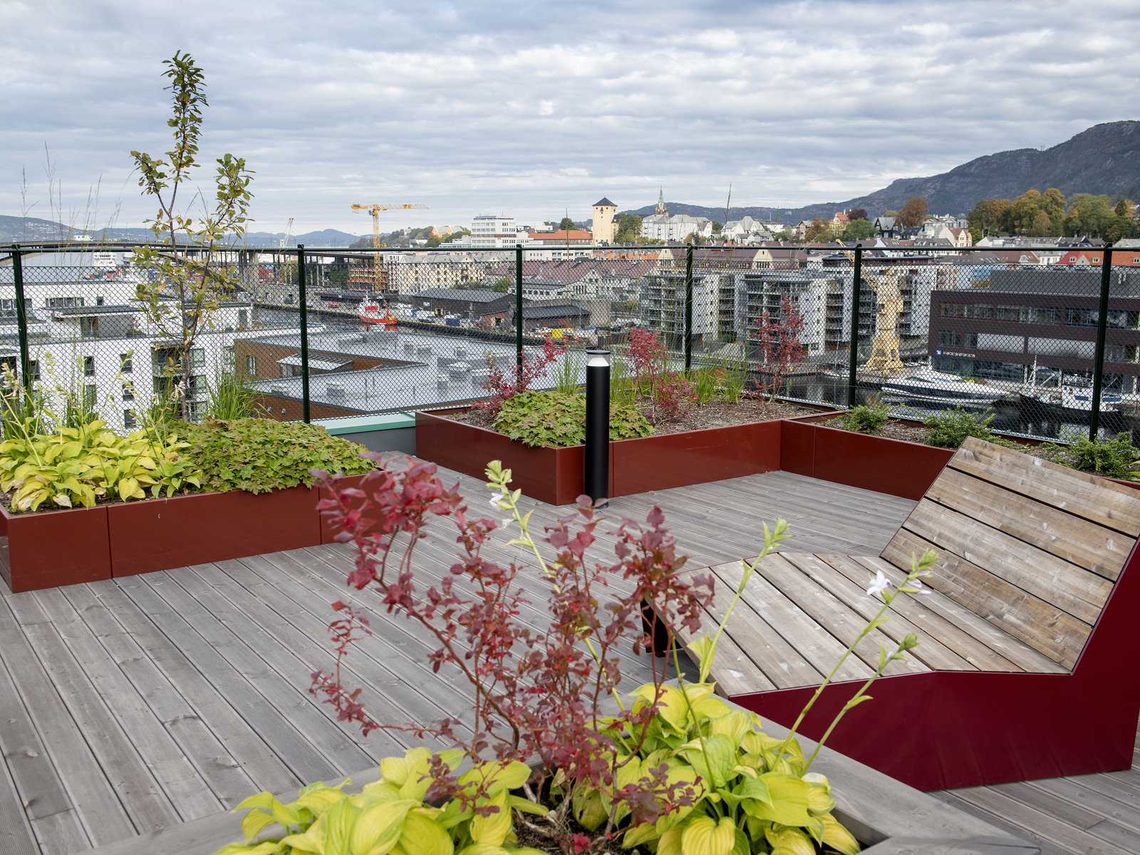 Takterrasse, utsikt over byen, stol og takhage i kasser. Foto.