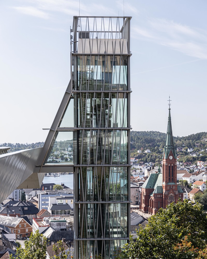 Foto av glassheisen med den nygotiske Trefoldighetskirken i bakgrunnen.