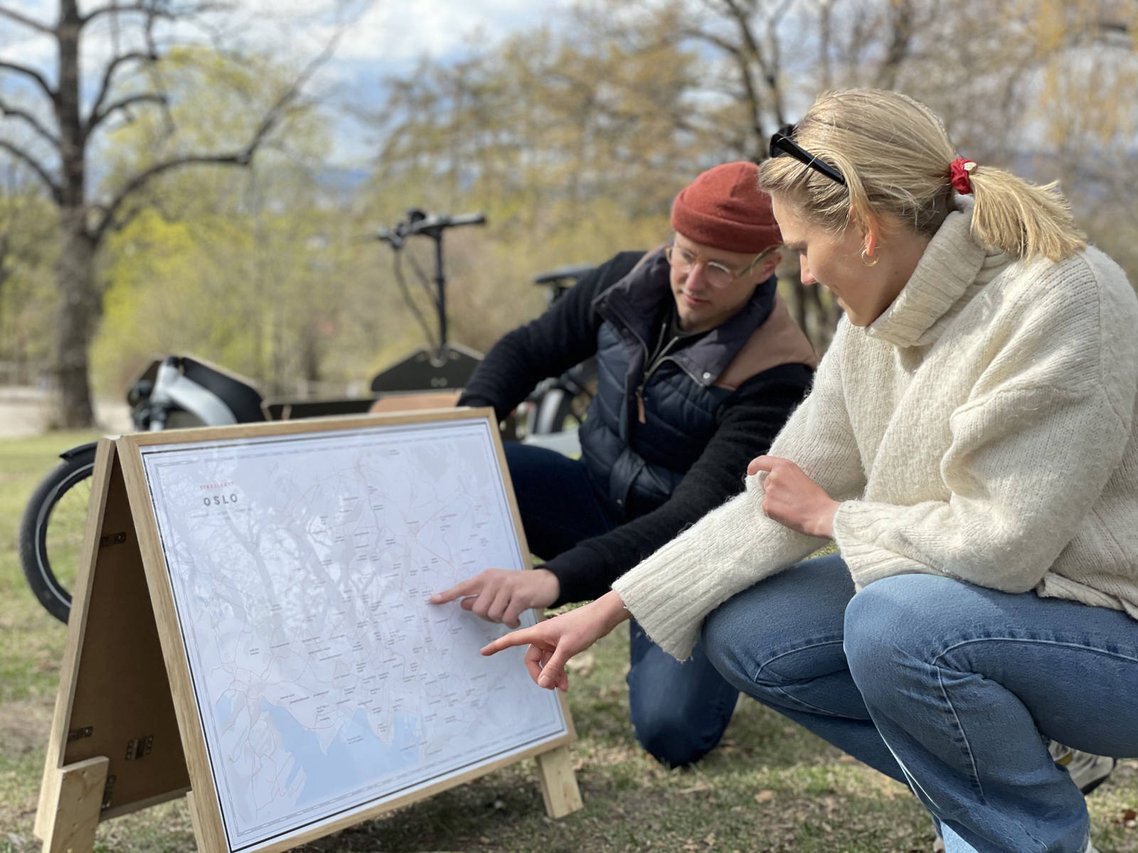 Daniel Andersson og en dame sitter på huk i en park og ser på et kart. Foto.