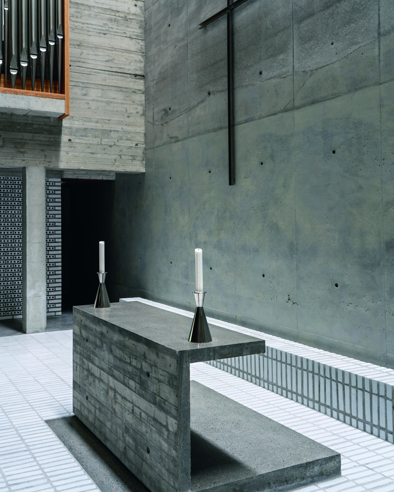 Alter i betong, bakvegg i betong gulv i hvit tegl. Foto.