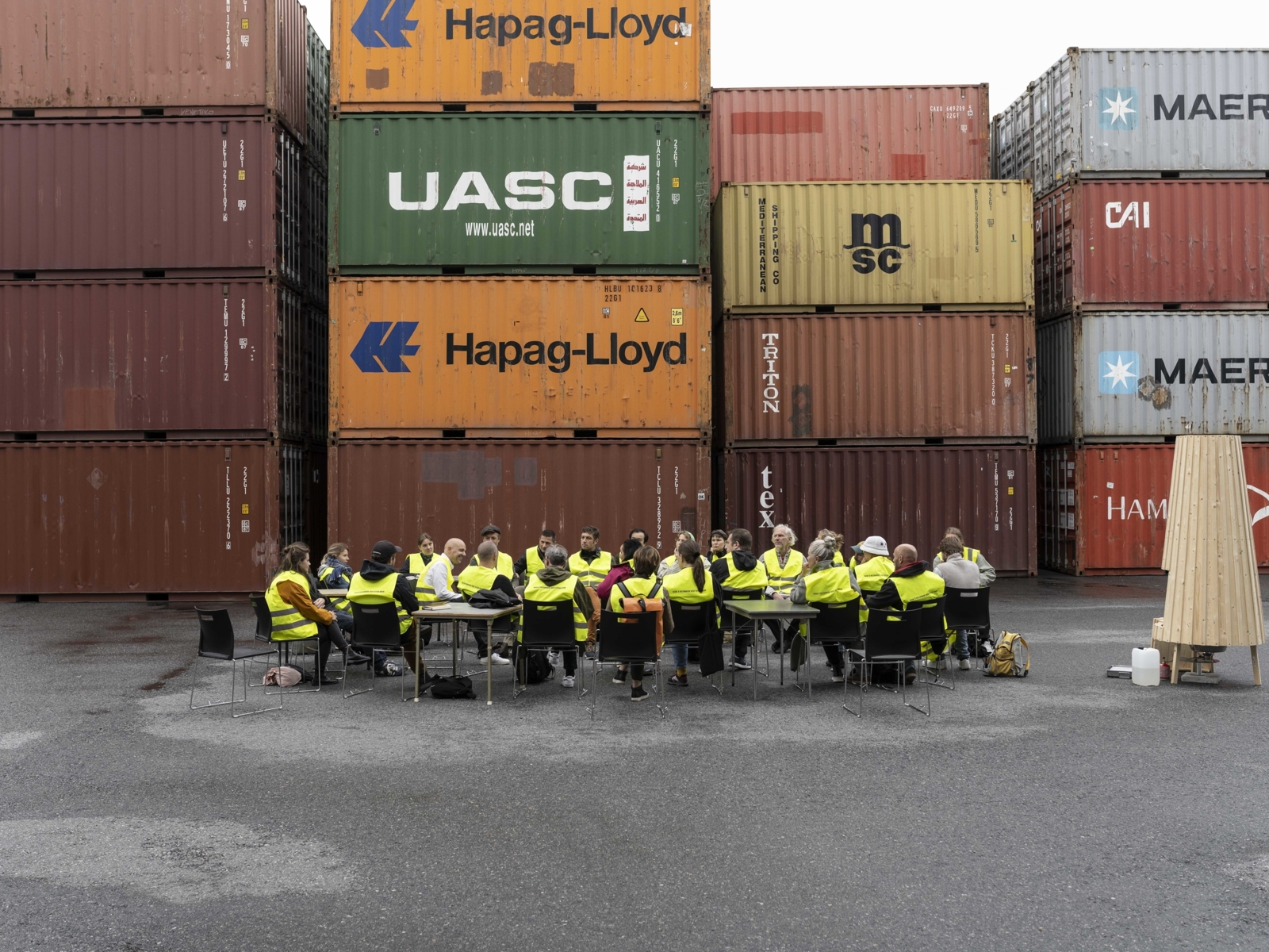 Foto av en gruppe i gul vest foran containere.