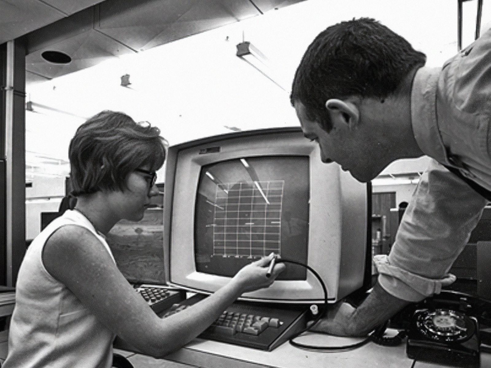 En mann og en kvinne jobber med en datamaskin i 1967. Svart hvitt foto.