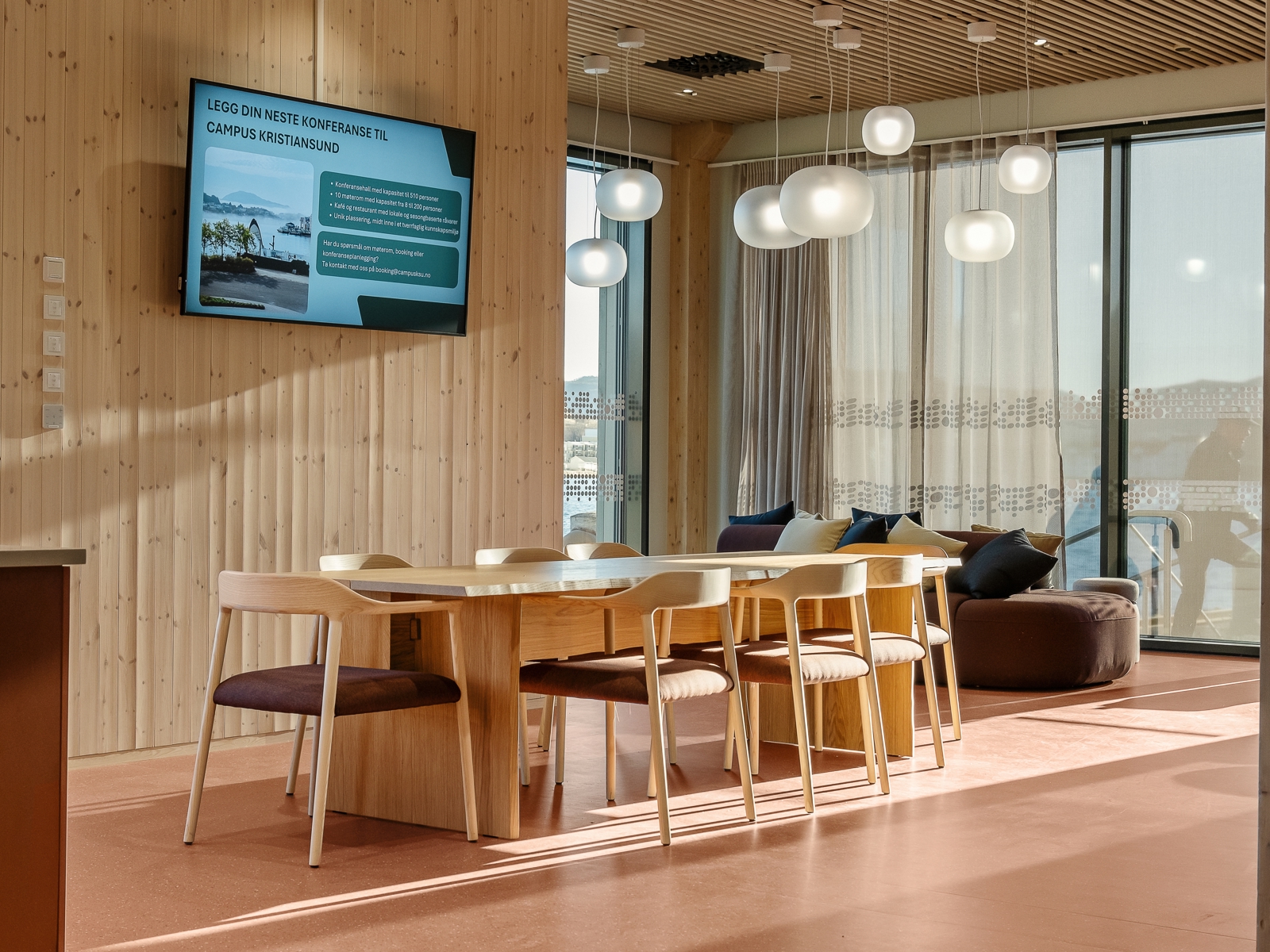 Interiør foto av møterom, treverk og røde toner.