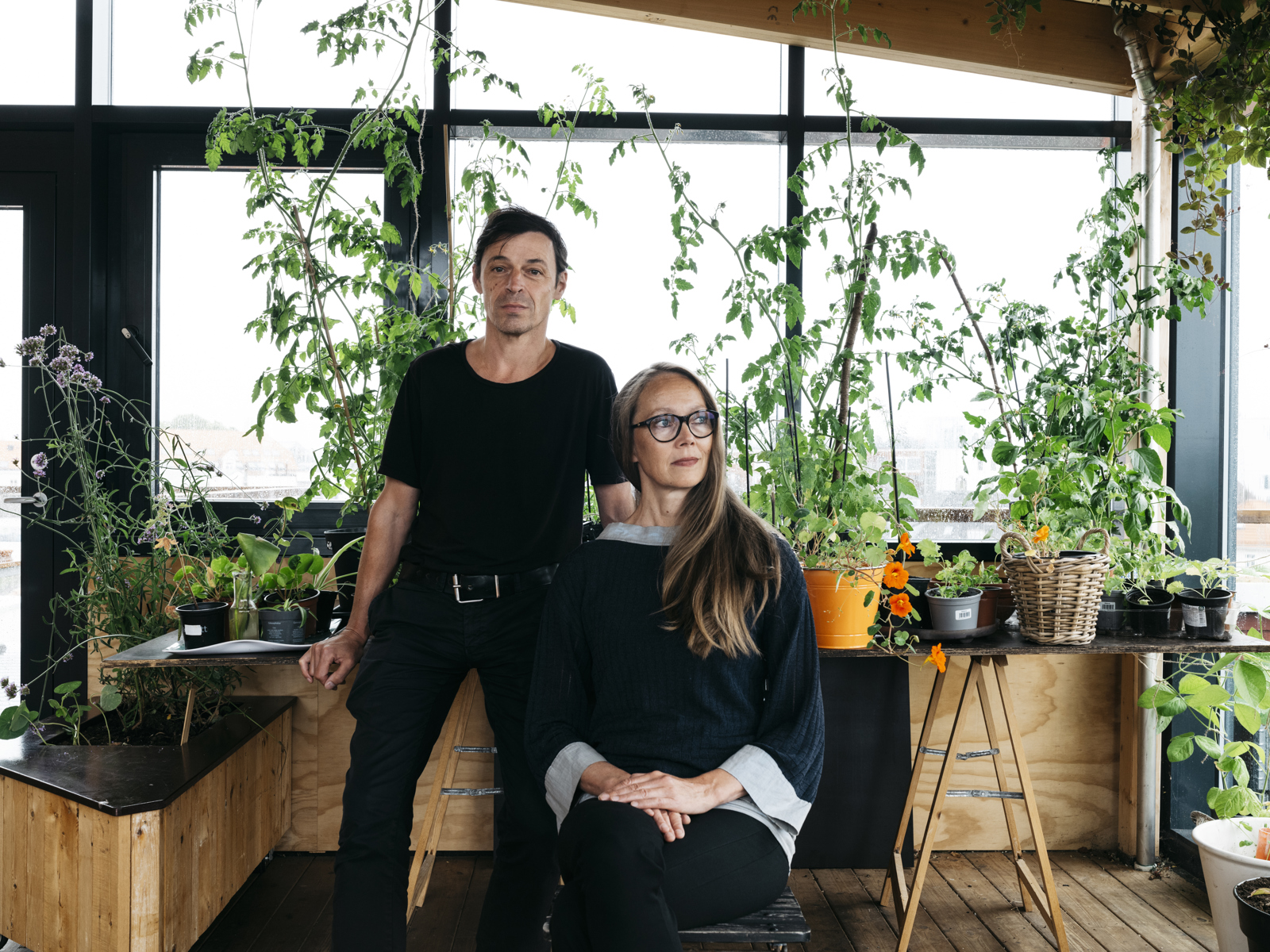 Foto av Reinhard Kropf som står og Siv Helene Stangeland som sitter, mange planter i bakgrunnen.