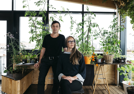 Foto av Reinhard Kropf som står og Siv Helene Stangeland som sitter, mange planter i bakgrunnen.
