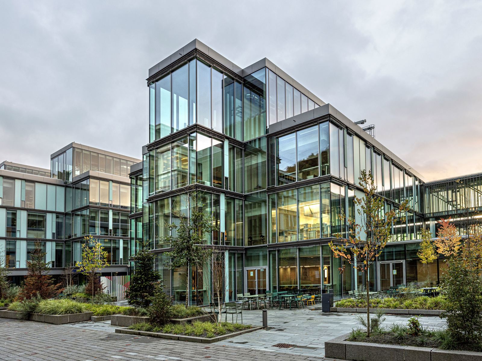 Foto av fasaden på Glasblokkene, vegetasjon og hardt underlag på plassen fremfor.