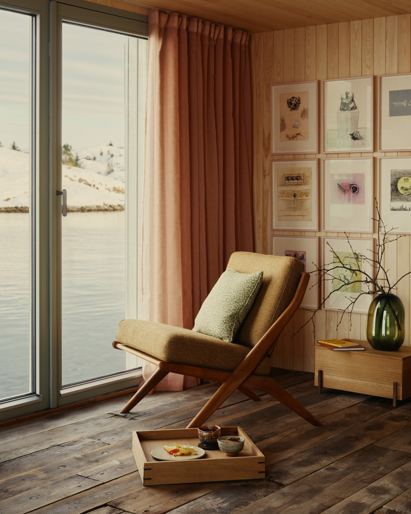 Foto av en stol ved et stort vindu med utsikt ut til havet.