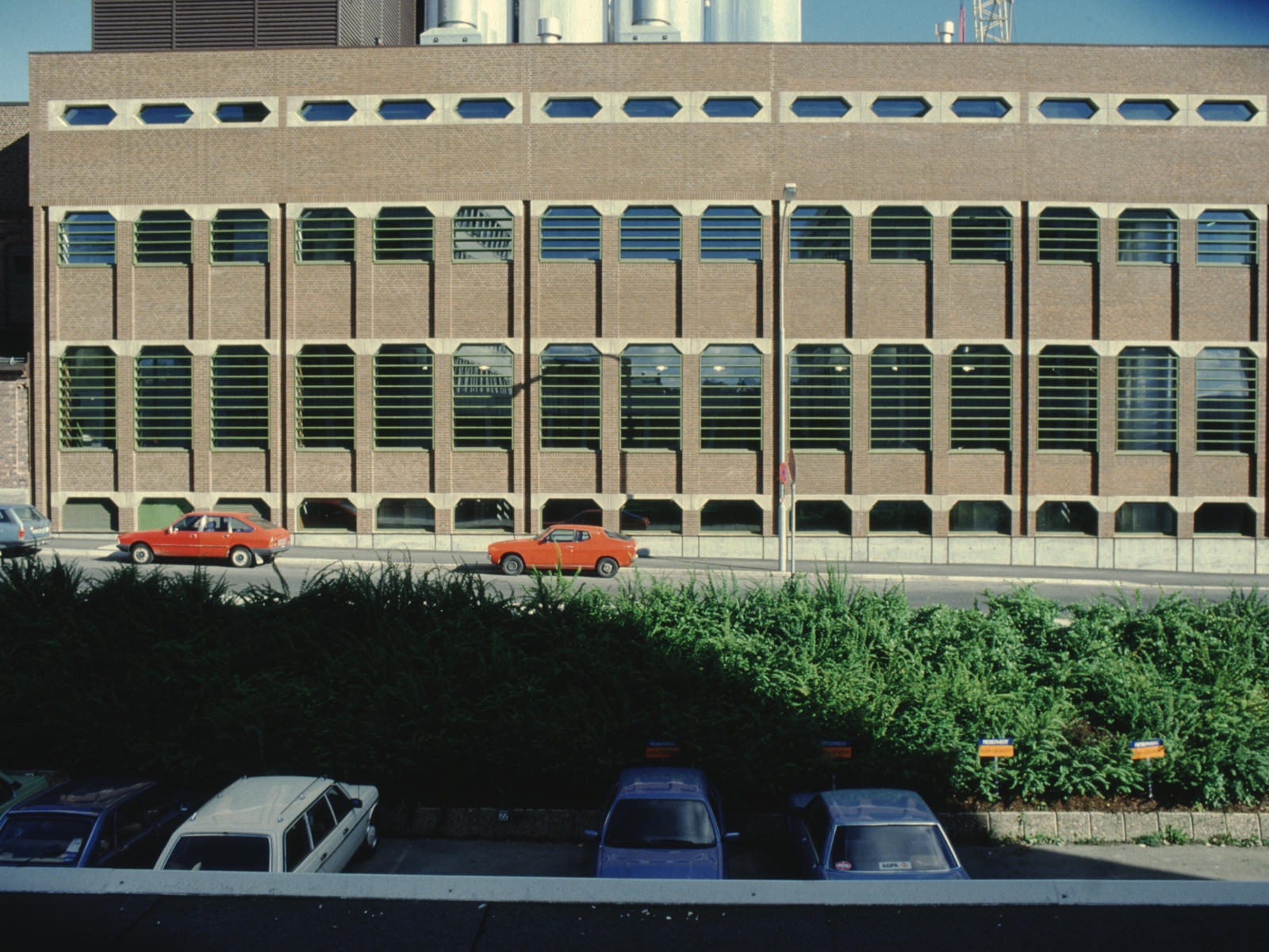 Eksteriørfoto av Ringnes bryggeri sin bryggerihall fra 1980-tallet, med fasade i tegl og vindusflater med grønne sprosser