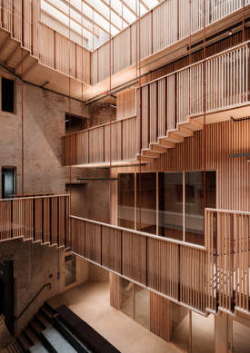 Utsikt inn i innvendig atrium mellom eldre bygårdsbygg. Svalganger beveger seg opp rundt atriumet med overlys. Foto.