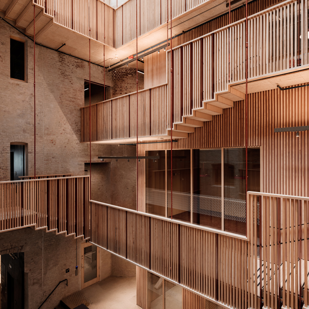Utsikt inn i innvendig atrium mellom eldre bygårdsbygg. Svalganger beveger seg opp rundt atriumet med overlys. Foto.