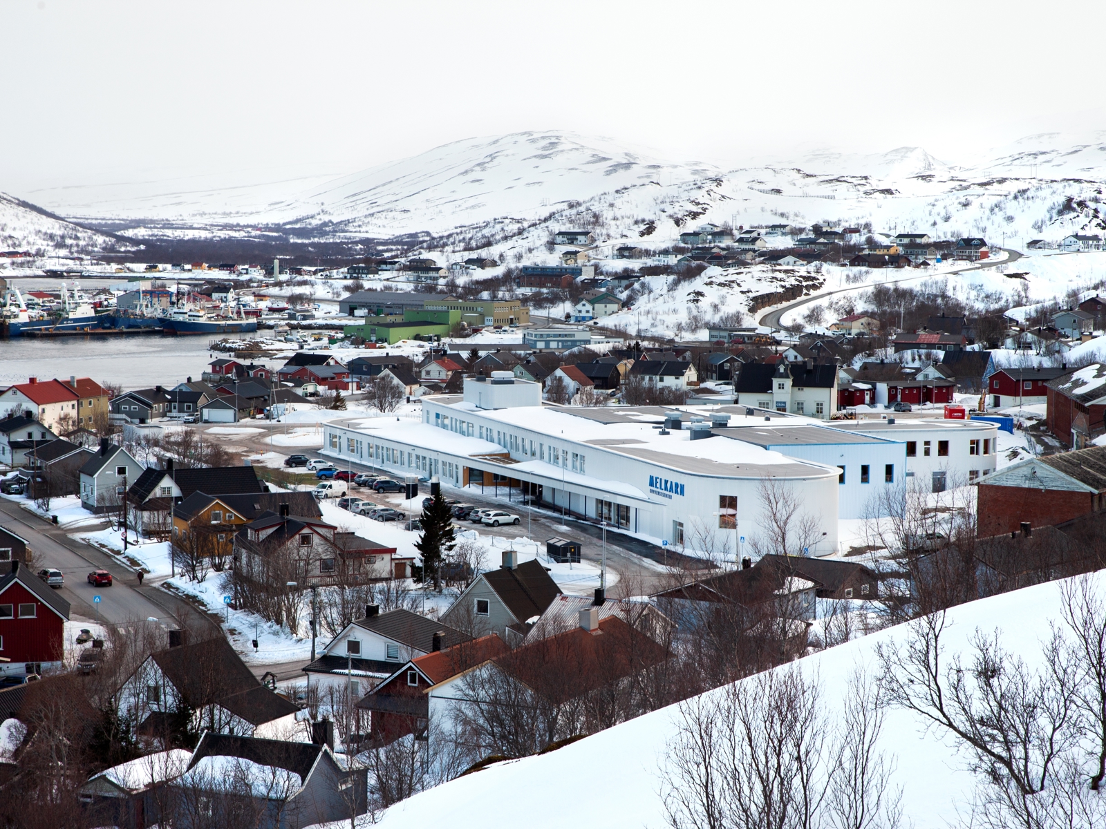 Oversikts foto av skole i snøkledd bygd. 