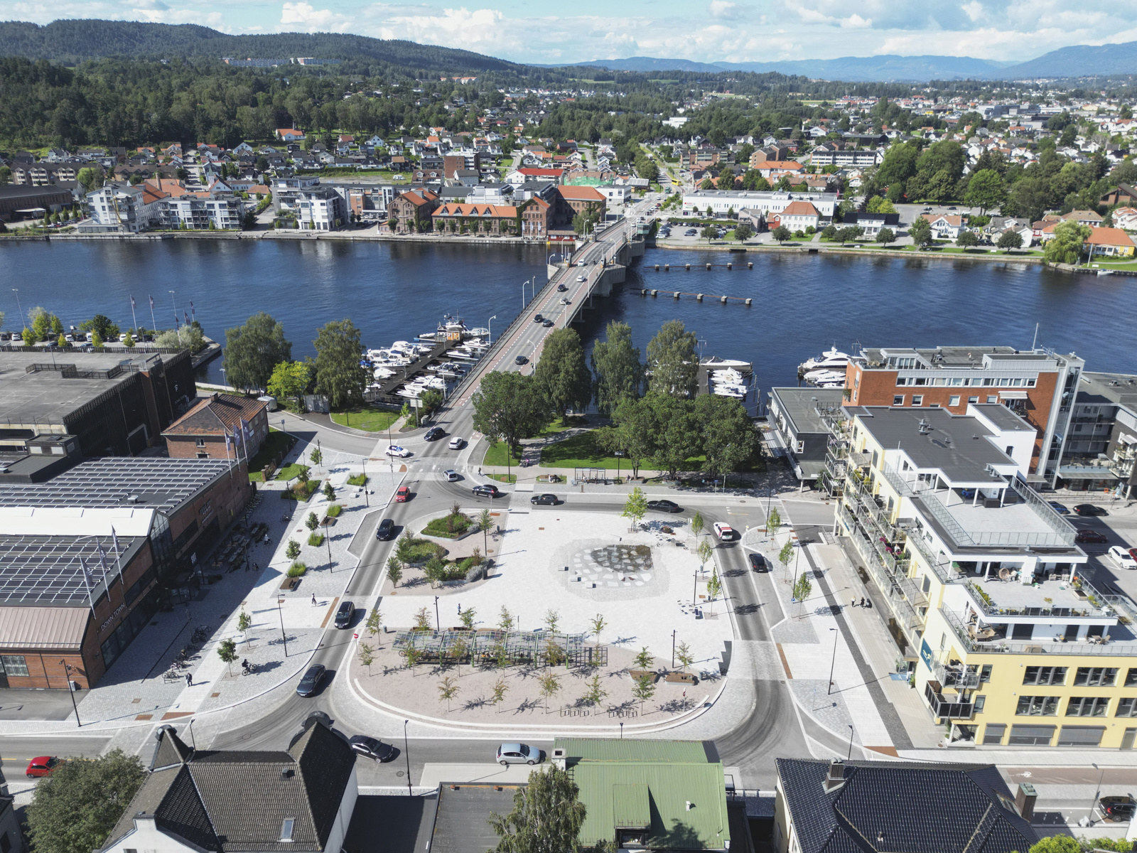 Oversiktsbilde av torg omsluttet av vei og bykontekst, liggende ved havet og bro. Drone foto.