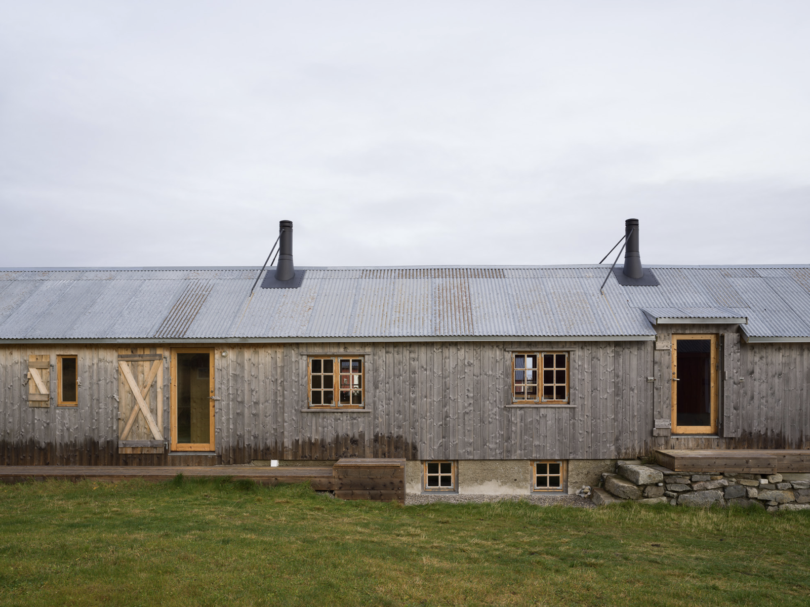 Foto av et langt grånet bygg, grønn plen i front.