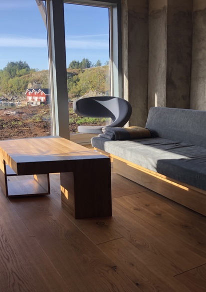 Foto av stue med tilpassede møbler i treverk, utsikt til natur.