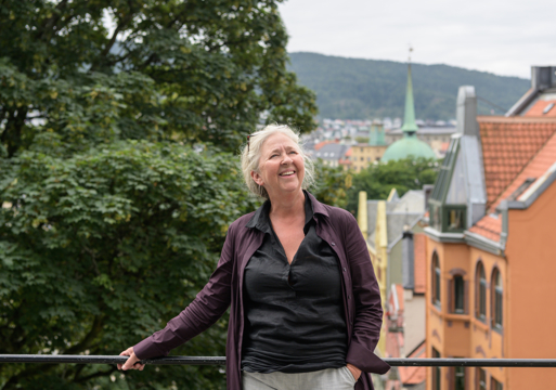 Maria Molden utendørs og lener seg inntil et rekkverk. Foto.