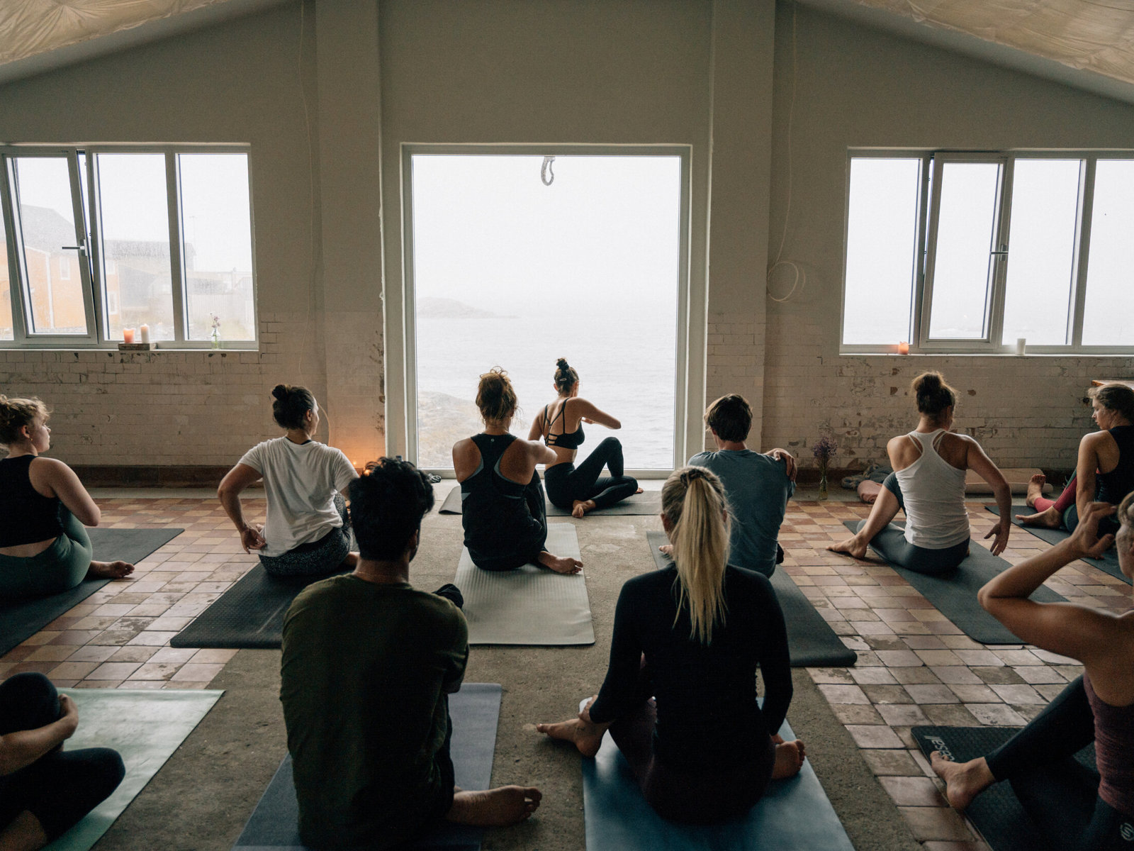 Foto av yoga klasse med store vinduer ut til et tåke landskap.
