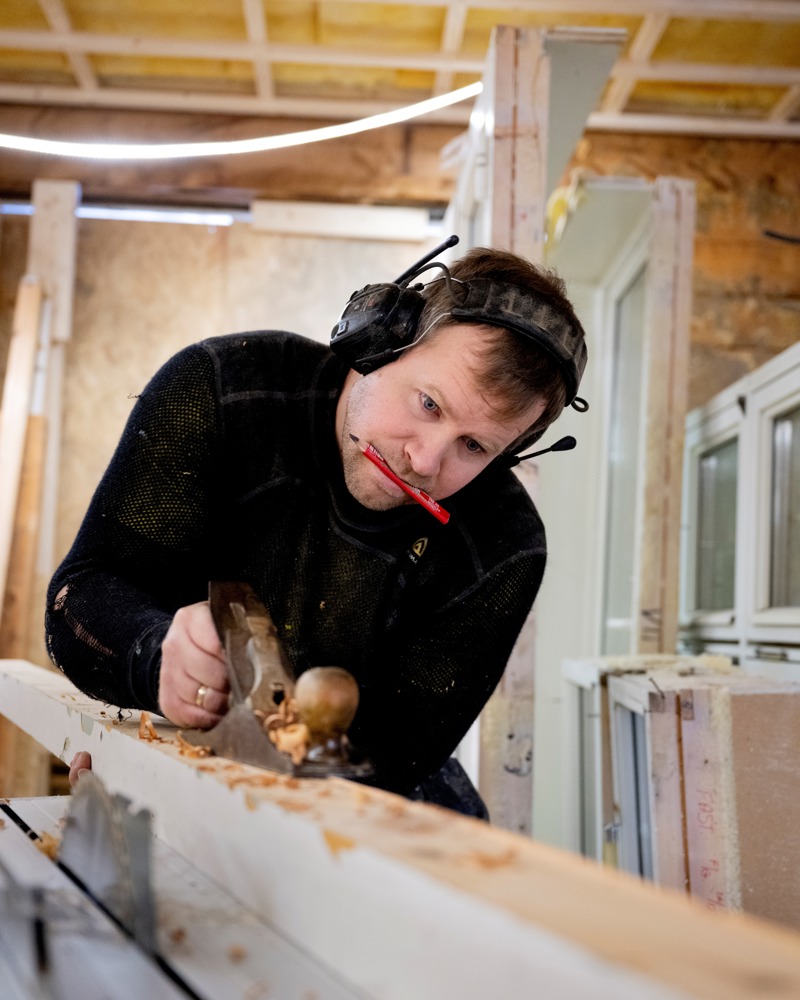 Foto av Vegard Mong som høvler en bjelke.