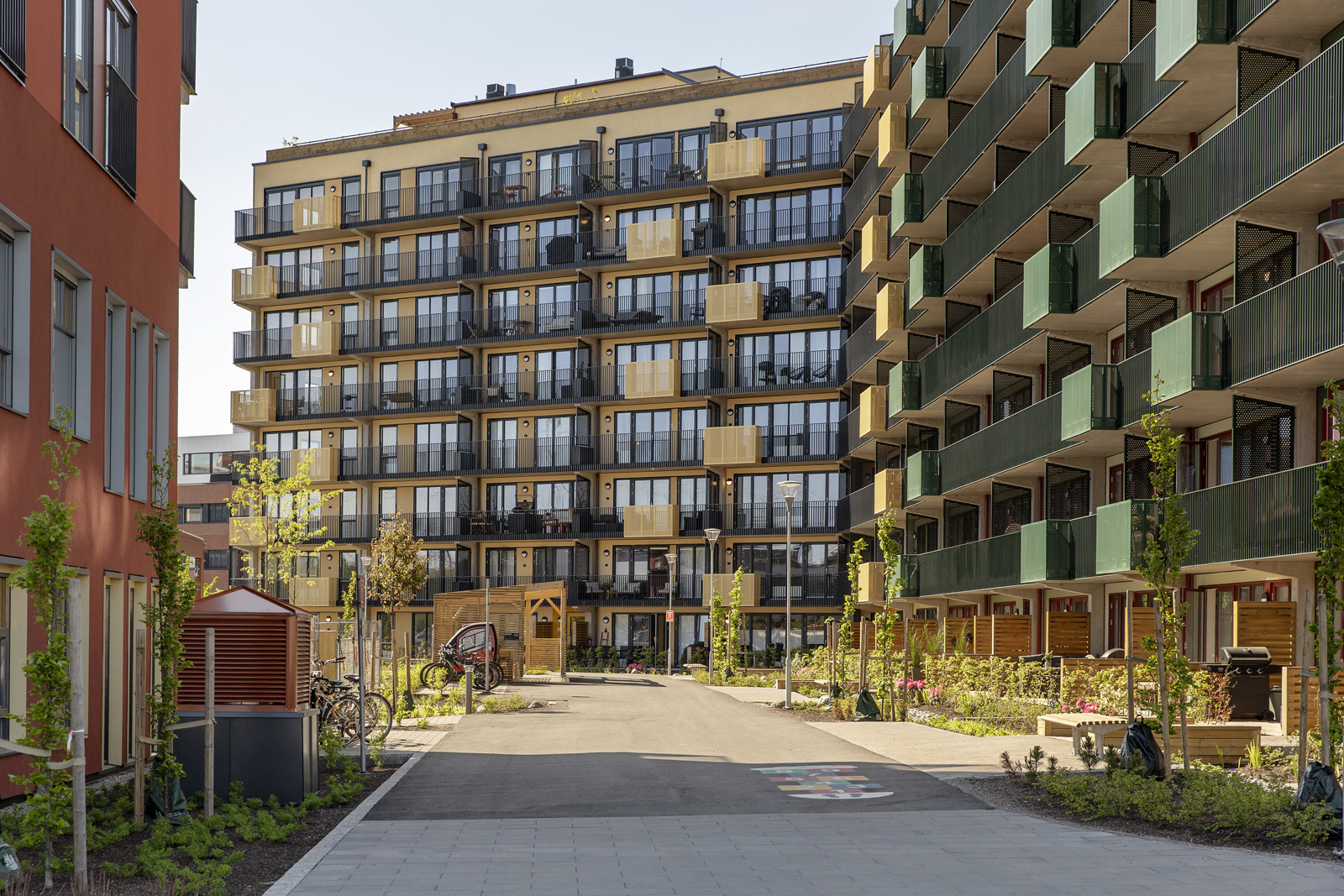 Foto mellom fargerike boligbygg, nedover en gate med grøntareal langs kantene.